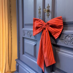 Große rote Stoffschleife an einer blauen Holztür, als weihnachtliche Dekoration