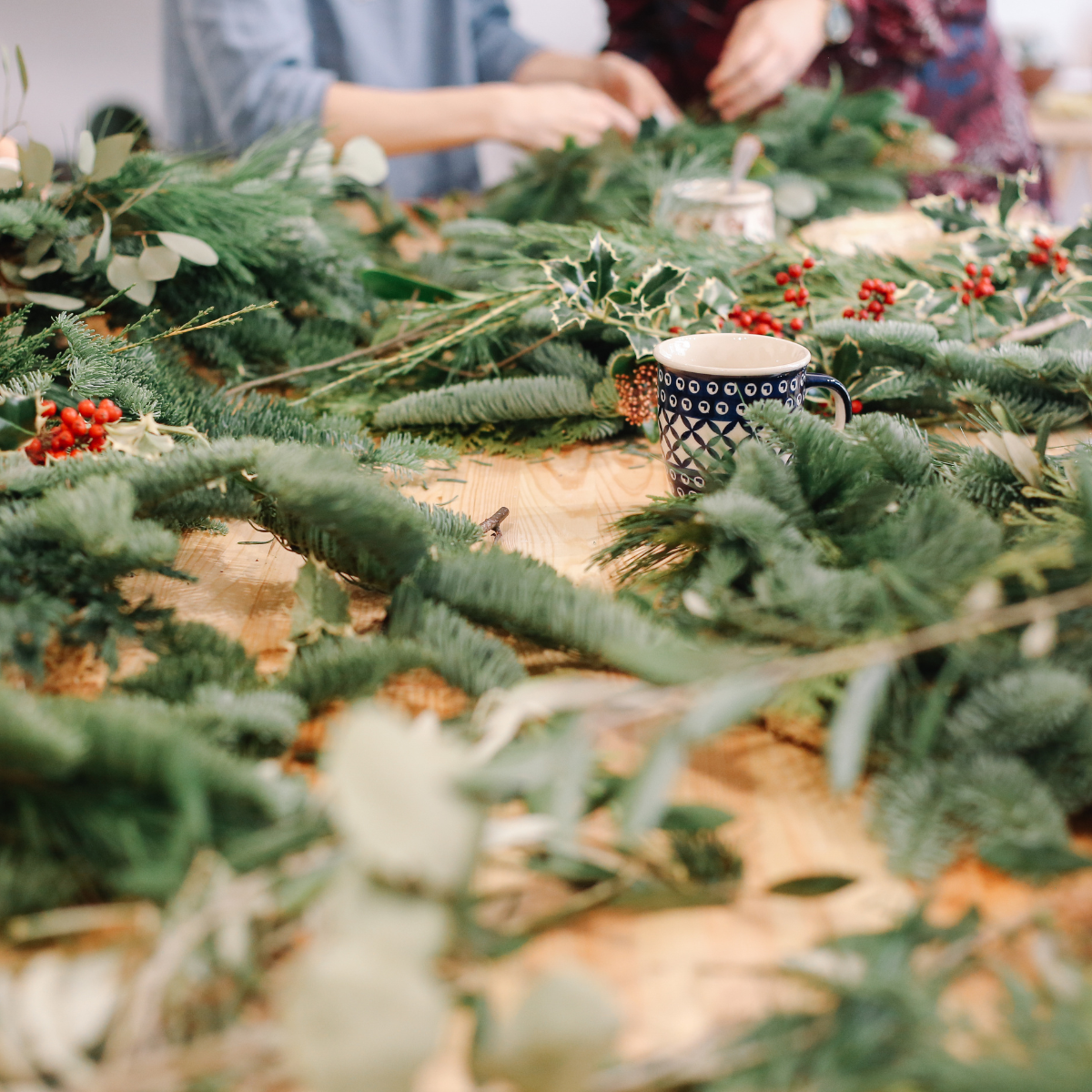 Werktisch mit frischem Tannengrün und Zweigen zum Adventskranz binden